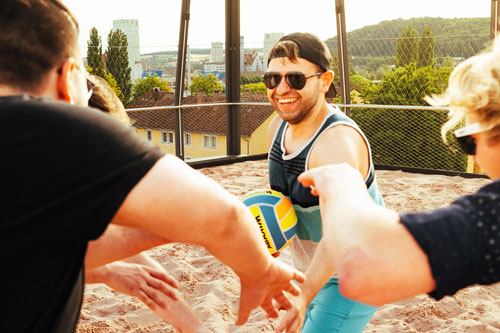 glückliche Menschen auf einem Volleyballfeld" title="Volleyballspiel bei e2n