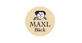 goldgelber Kreis. Innerhalb des Kreises steht MAXL Bäck und darüber ist ein illustriertes Gesicht eines Jungen." title="Logo Maxl Bäck