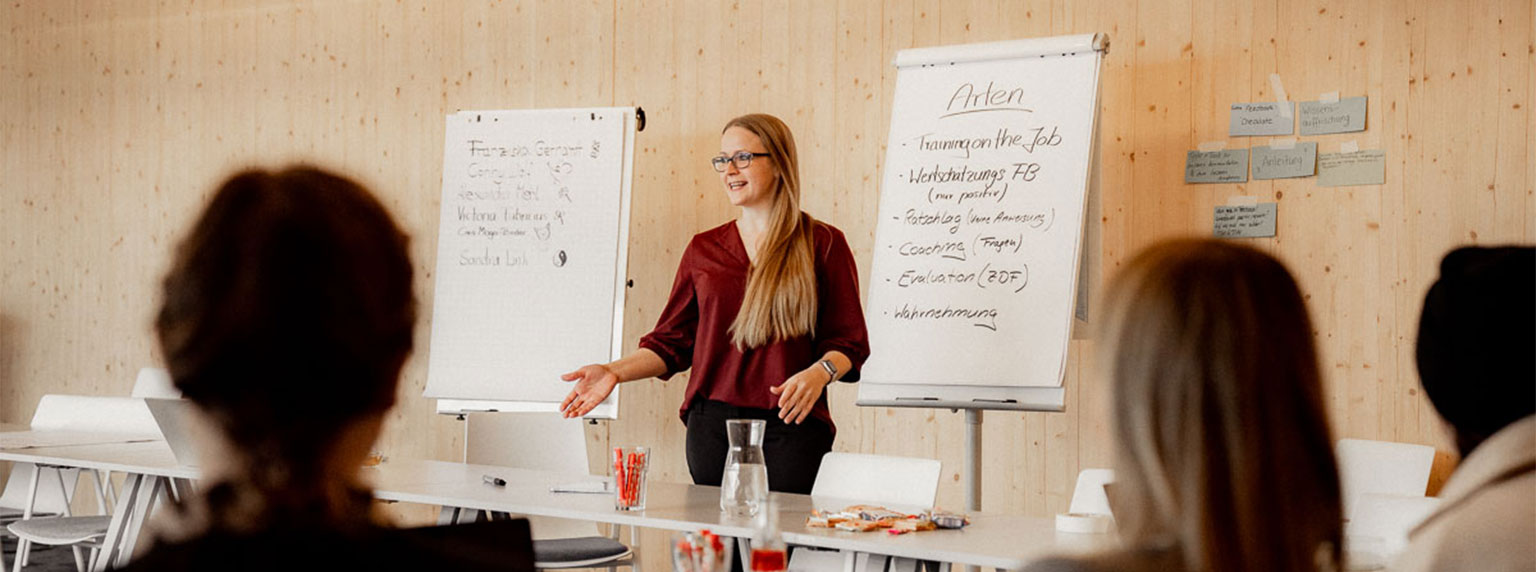 Frau hält vor einer Gruppe von Menschen ein Seminar" title="Franziska e2n Kommunikationstrainerin bei einem Seminar