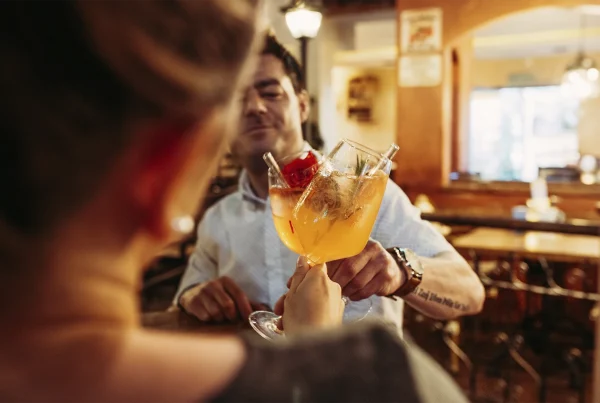 zwei Personen stoßen mit zwei Cocktails an auf die Senkung der Mehrwertsteuer in der Gastronomie
