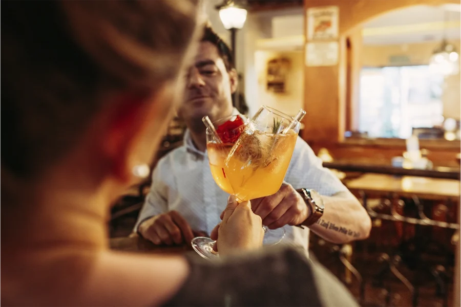 zwei Personen stoßen mit zwei Cocktails an auf die Senkung der Mehrwertsteuer in der Gastronomie