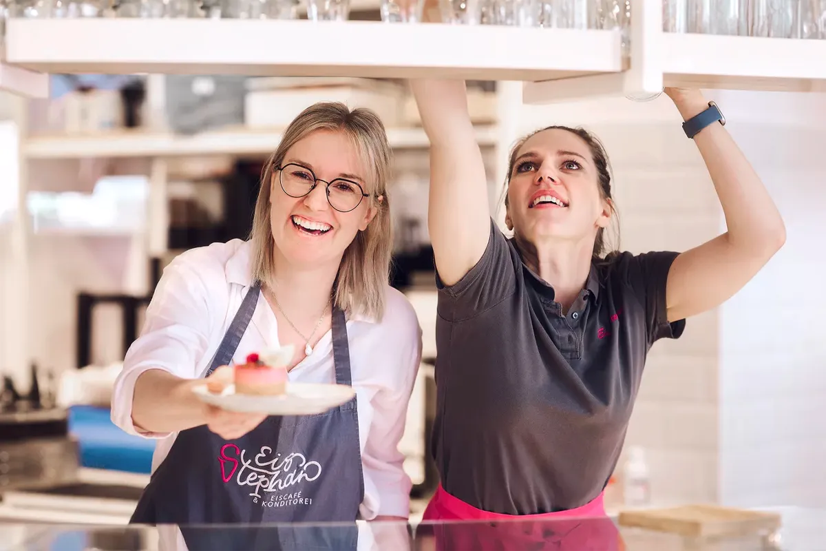 zwei Frauen lächelnd bei der Arbeit